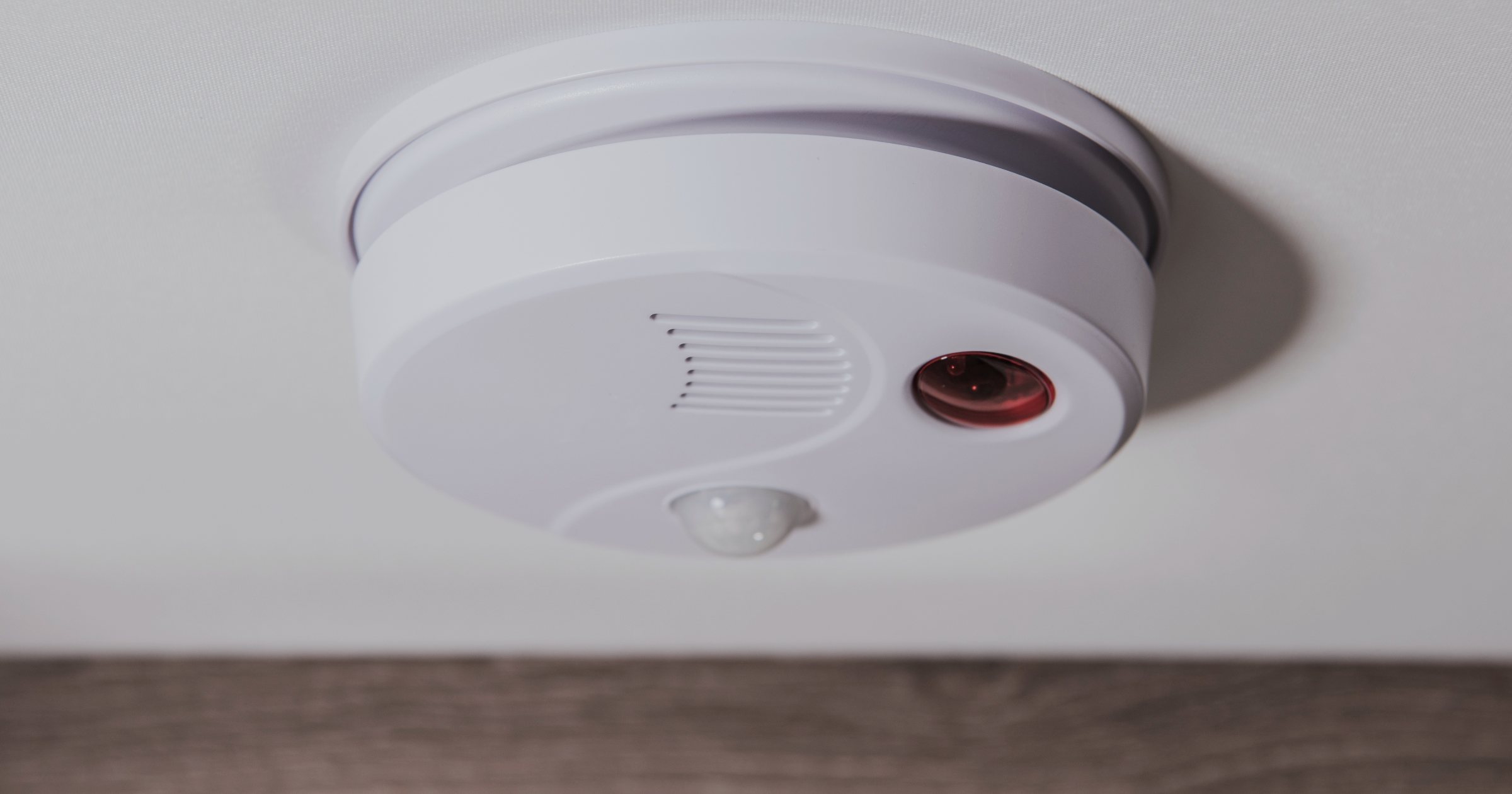 Detector de gaze rotund alb montat pe tavanul unei locuințe, lângă perete